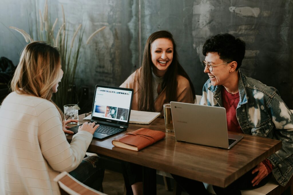 Three young professionals laughing and working on laptops, representing a friendly professional house share in Cheltenham