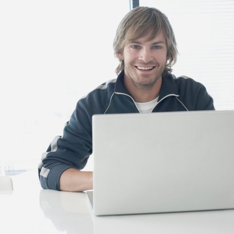 Lewis, a student from 2021-22, smiling and working on a laptop.